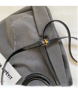 Detail of adjustable black leather strap with gold buckle on a stylish blazer