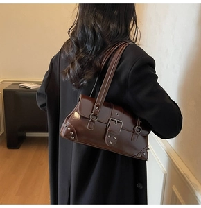 Détail d'un sac sous le bras marron foncé brillant avec rivets argentés et boucle métal