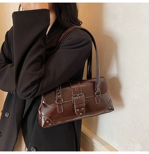 Détail de texture cuir marron foncé avec rivets métalliques et boucle sur sac sous le bras