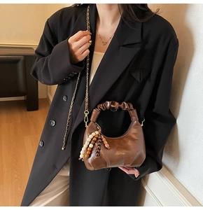 Detail of dark brown leather crescent bag with ruched handle and beaded tassel