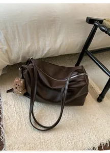 Deep brown leather tote bag with silver zipper and cute plush bear charm detail