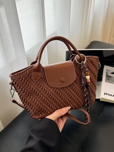 Brown woven texture handbag with leather flap and wood bead tassel charm on a chair