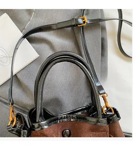 Detail of suede tote bag handle with black leather trim and polished gold hardware