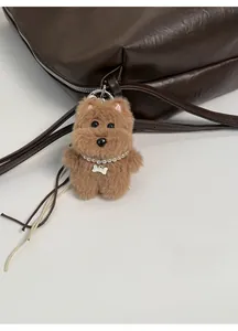Detail of brown plush puppy bag charm with pearl necklace and metal bone pendant