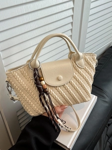 Chic beige woven texture handbag with dual top handles and decorative charm detail