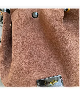 Detailed macro view of soft brown suede material and golden logo on the bucket bag