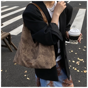 Brown faux suede tote bag with minimalist triangular silhouette shown on a street set