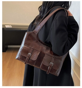 Close-up of deep brown oil wax leather shoulder bag with double buckled flap pockets
