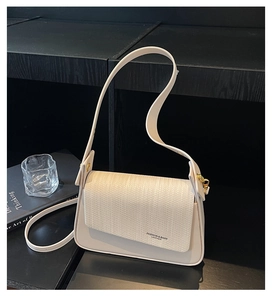 Detail of white leather handbag showing woven texture flap and gold metal hardware
