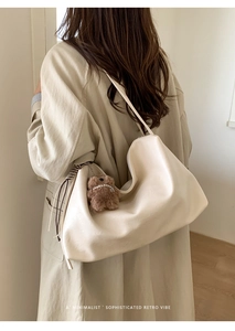 Minimalist beige tote bag with cute plush bear charm shown in a soft lifestyle setting