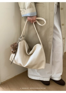 Detail of off-white hobo bag with soft leather texture and brown plush bear charm