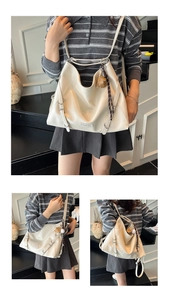 Macro detail of creamy white oversized tote bag with decorative belts and cute bear charm