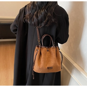 Brown faux suede drawstring bucket bag detail with leather handles and crossbody strap
