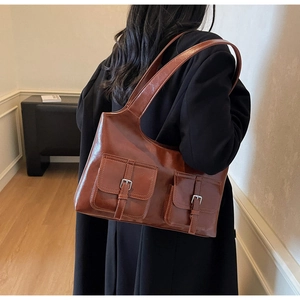 Close-up of vintage brown leather underarm bag with symmetrical front flap pockets