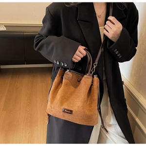 Brown suede bucket bag detail with drawstring closure and dark leather strap shown on model