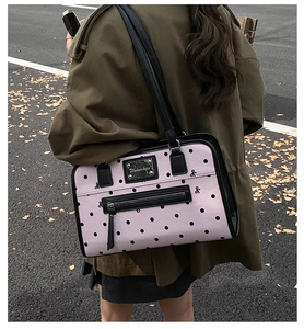 Detail of pink canvas tote with black polka dots, leather trim, and embroidery