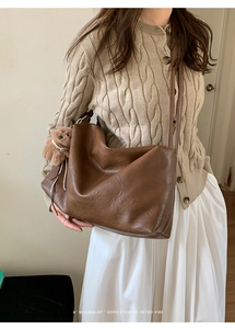 Brown retro tote bag with plush bear charm worn by model in beige knit cardigan