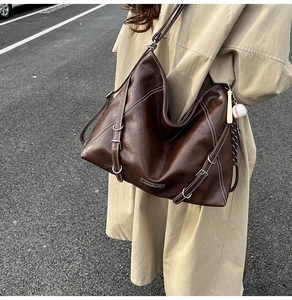 Detail of dark brown hobo bag with contrast stitching and metallic buckle accents
