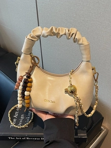 Beige pleated crescent handbag with wooden beads and woven metal chain strap
