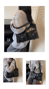 Macro detail of retro black shoulder bag with dual flap pockets and silver metal buckles
