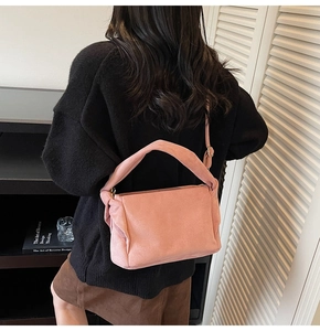 Detail of pink suede shoulder bag with pleated sides and adjustable crossbody strap