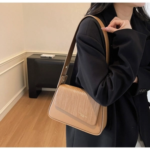Close-up of brown crossbody bag with woven texture flap and wide shoulder strap