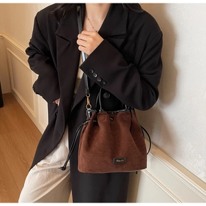 Detail of dark brown faux suede bucket bag with drawstring closure and leather trim