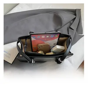 Detail shot showing the large interior capacity of a black tote bag with tablet and phone