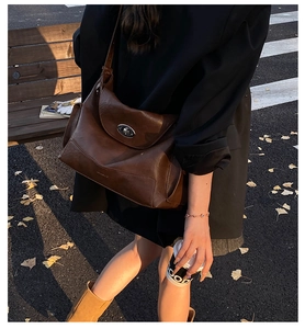 Detail of a large brown oil wax leather tote bag with a metal oval twist lock closure