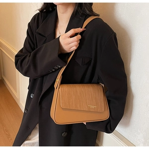Detail of caramel leather crossbody bag featuring wide shoulder strap and gold logo