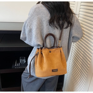 Brown suede bucket bag with drawstring closure worn by model in minimalist home setting