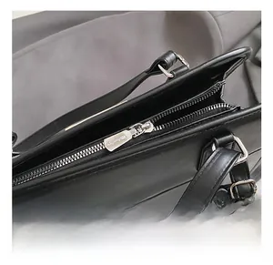 Close-up of premium metal hardware with polished zipper and D-ring on a black leather bag