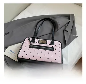 Detailed view of pink polka dot handbag with black leather trim on a stylish suit