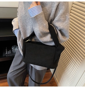 Detail of a black matte nylon shoulder bag with side ear design and gold metal hardware