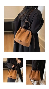Detail of brown faux suede bucket bag showing drawstring closure and leather logo patch