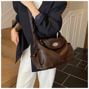 Detail of dark brown leather tote bag with silver metal buckle and side flap pockets