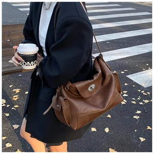 Detailed side view of dark brown faux leather tote bag with functional side pocket