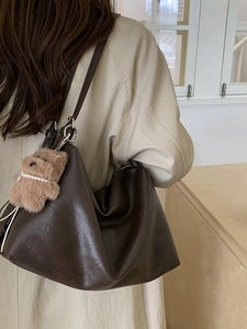 Retro dark brown oversized tote bag with plush bear charm worn with beige trench coat