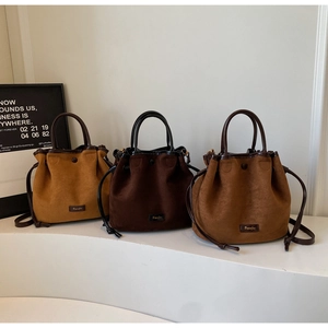 Three suede bucket bags in different brown tones displayed on white steps showing texture