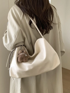 Chic cream oversized hobo bag on shoulder with cute plush bear charm decoration