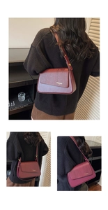 Detail of burgundy crossbody bag with woven texture flap and gold hardware accents