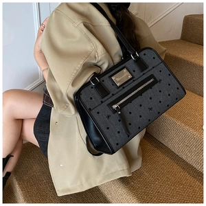 Polka dot fabric shoulder bag with leather trim and fringe detail worn by model on stairs