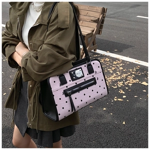 Close-up of pink polka dot shoulder bag with bow pattern and metal logo plate