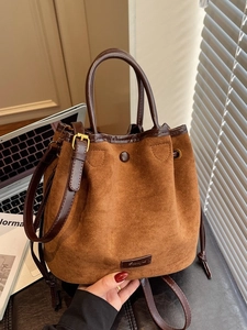 Caramel faux suede drawstring bucket bag with leather handles and metallic brand plate
