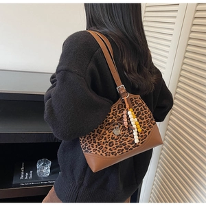Detail of leopard print shoulder bag featuring brown leather trim and beaded charms