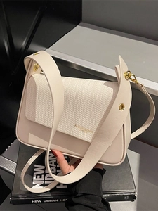 Minimalist beige crossbody bag featuring woven texture flap and wide leather shoulder strap