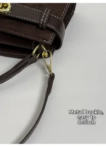 Detalle de la hebilla de metal dorado y correa desmontable en bolso de cuero marrón