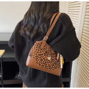 Leopard print shoulder bag with bow and heart charm shown on model in modern room