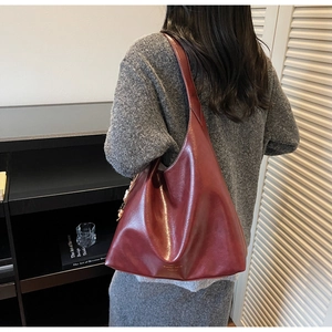 Detail of burgundy PU leather tote bag with wide shoulder strap and white stitching