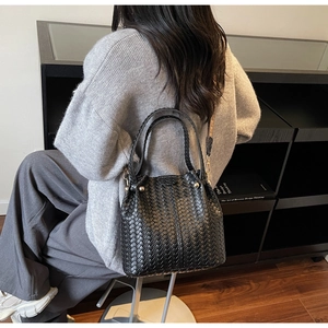 Close-up of black woven tote bag with intricate texture and decorative ethnic strap